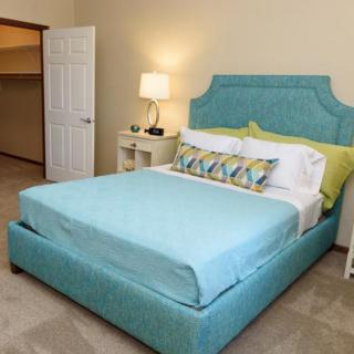 A neatly arranged bedroom with a blue upholstered bed and matching decor.