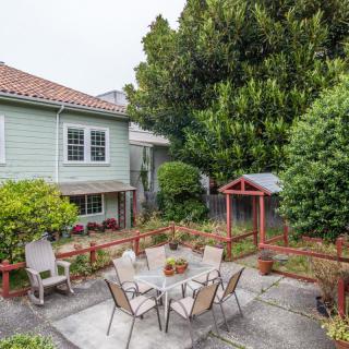A cozy backyard patio area with a table and chairs, surrounded by lush greenery.