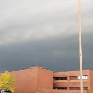 A dark and gloomy sky looms over a brick building, hinting at an approaching storm.