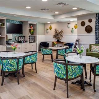 A cozy and modern dining area with colorful chairs and tables, featuring decorative elements on the walls and a television.