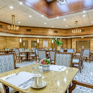 An elegant dining room with neatly arranged tables and chairs, adorned with chandeliers and tasteful decor.