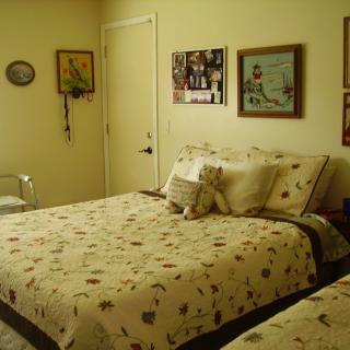 A cozy bedroom with floral-patterned bedding and wall art.