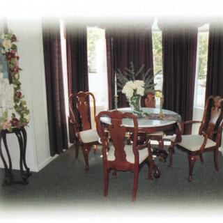 A classic dining room setup featuring a round table with wooden chairs and elegant curtains.