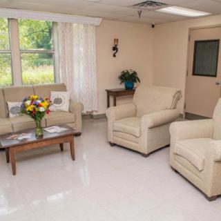 A cozy living room with comfortable armchairs, a sofa, and a coffee table adorned with fresh flowers.