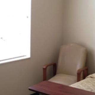 A minimalist room with a chair by the bed and a window.