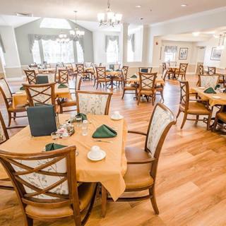 An elegantly set dining room with multiple tables and chairs, ready for guests.