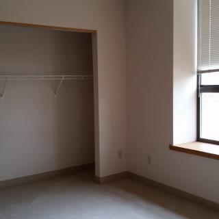 An empty room with a closet and a window, showcasing a minimalist interior.