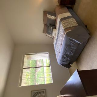 A cozy bedroom featuring a neatly made bed, a window allowing natural light, and simple decor.