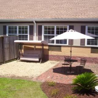 A cozy backyard patio with a swing, outdoor seating, and an umbrella.