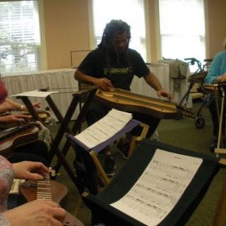 A group of musicians playing dulcimers in an indoor setting.