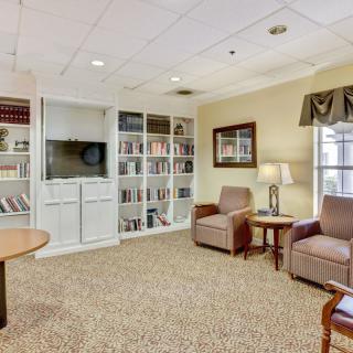 A cozy living room with a seating area, bookshelves, and a television.