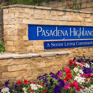 Entrance sign for Pasadena Highlands, a senior living community, surrounded by colorful flowers.