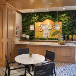 A cozy indoor cafe with a green wall, wooden paneling, and a seating area featuring a round table and chairs.