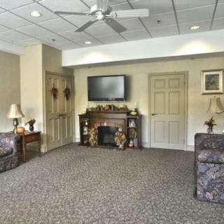 A cozy living room with a fireplace and television, featuring comfortable seating and decorative elements.