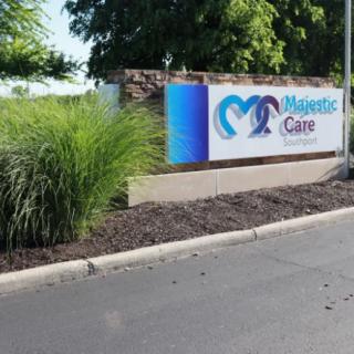 A healthcare facility sign with landscaping along a road.