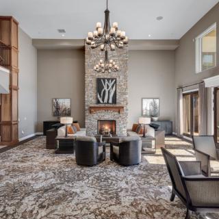 A luxurious living room features a grand chandelier, modern seating around a cozy fireplace, and elegant interior design.
