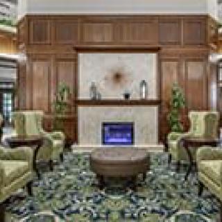A cozy lobby with elegant chairs, a fireplace, and decorative plants.