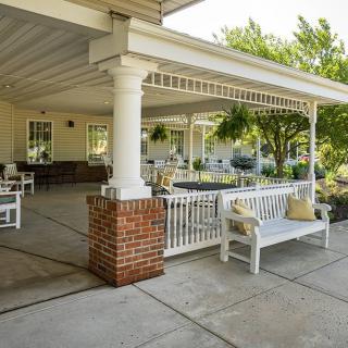 A spacious outdoor patio with white benches and a covered seating area.