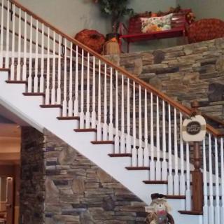 A beautifully designed indoor staircase with a stone wall and decorative railing.