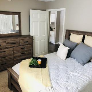 A cozy bedroom featuring a neatly made bed with decorative pillows and a wooden dresser with a mirror.