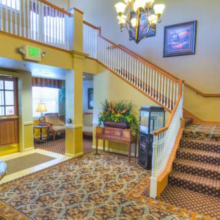 A cozy hotel lobby featuring a staircase and chandelier.