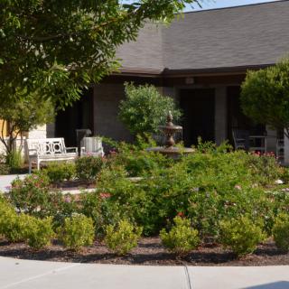 A well-maintained garden with a variety of plants and bushes in front of a building.