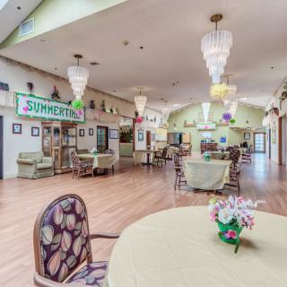 A bright and spacious dining area with decorative chandeliers and floral arrangements on tables.