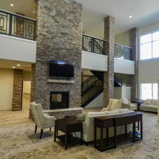 A spacious and modern living room with a central stone fireplace, comfortable seating, and a TV mounted above the fireplace.
