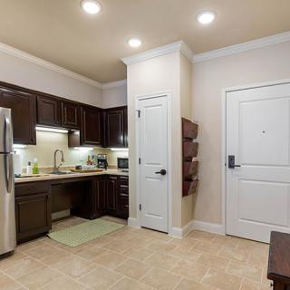 A modern kitchen with stainless steel appliances and wood cabinetry in an apartment setting.