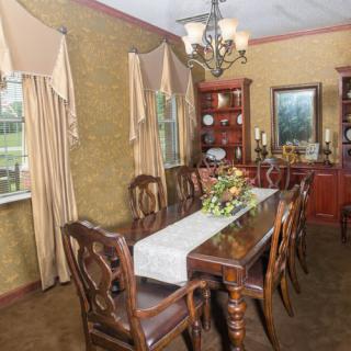 An elegant dining room featuring classic wooden furniture and a central chandelier.