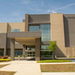 A modern educational building with large windows and landscaped surroundings.