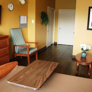 A cozy hotel room with warm-colored walls, featuring a bed, wooden furniture, and simple decor.