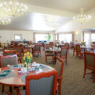 A spacious dining area with elegantly arranged tables and chandeliers.