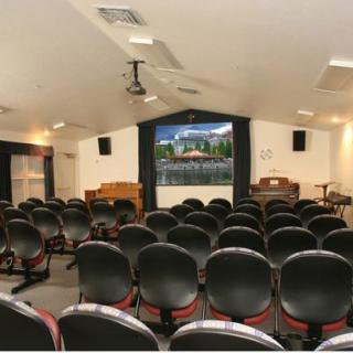 An empty auditorium with rows of chairs facing a screen and stage area.