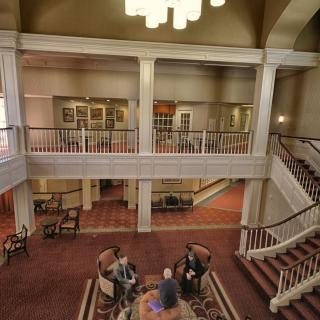 An elegant lobby with a staircase and seating area where people are gathered.