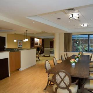 A modern dining area with a long wooden table and elegant chairs, featuring warm lighting and stylish decor.