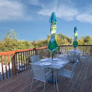 An inviting outdoor patio with tables and umbrellas set against a scenic backdrop.