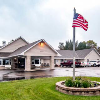 A building with an American flag flying in front of it, surrounded by a well-maintained lawn and a parking lot.