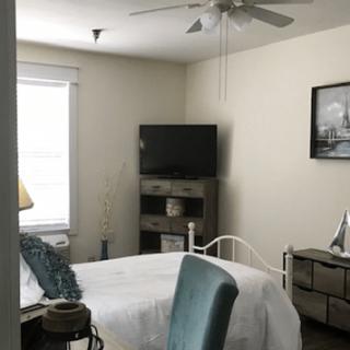 A cozy bedroom with a bed, television, and ceiling fan.