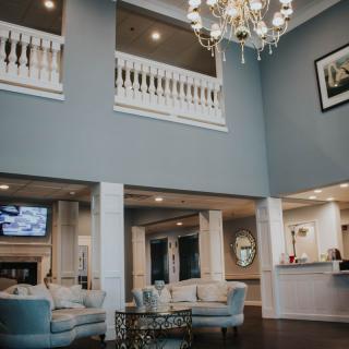 A modern, elegant lobby with a chandelier, seating area, and reception desk.