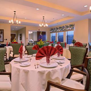 An elegantly set dining room with neatly arranged tables, chairs, and decorative chandeliers.