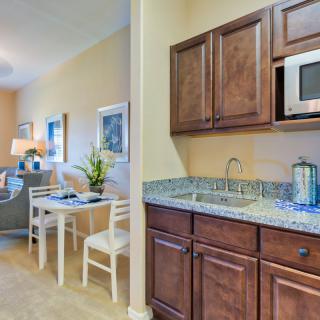 A cozy kitchen and dining area featuring wooden cabinets, a microwave, a sink, and a small dining table with chairs.