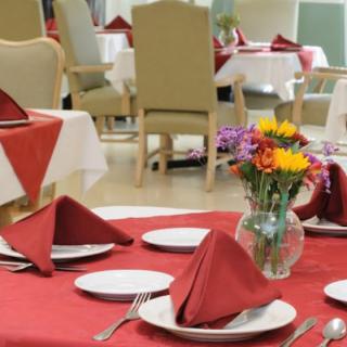 A beautifully set restaurant table with red napkins, plates, and a flower arrangement.