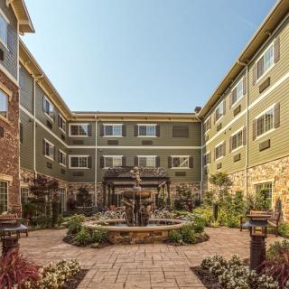 A serene courtyard with a central fountain, surrounded by a multi-story building and well-maintained landscaping.