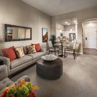 A cozy living room with neutral tones featuring a comfortable sofa, coffee table, and an adjacent dining area.