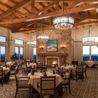 An elegantly designed restaurant dining room featuring chandeliers and a cozy fireplace.