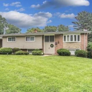 A suburban ranch-style house with a well-maintained lawn and a clear, cloudy sky.