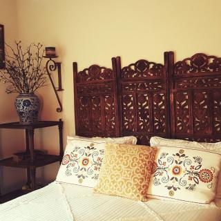 A cozy bedroom featuring a decorative wooden headboard and embroidered pillows.