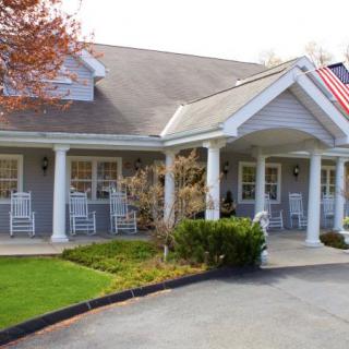 A charming house with a welcoming porch featuring rocking chairs and an American flag.
