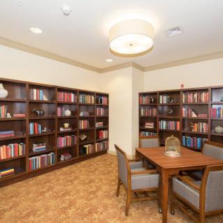 A cozy library reading area with bookshelves and a table surrounded by chairs.